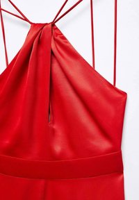 Robe en satin rouge avec un design à col halter, mettant en avant un corsage tordu et de fines bretelles ajustables, soulignant une texture lisse et un drapé élégant.