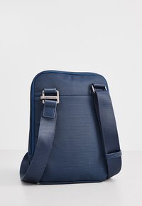 Borsa a tracolla blu navy con tessuto texturizzato, tracolla regolabile e hardware in argento. Presenta una chiusura con zip e angoli rinforzati.