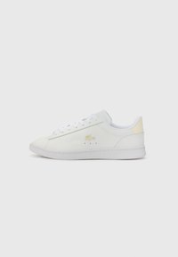 Hvit sneaker med glatt skinnoverside, rund tå, flate hvite snørebånd, gulllogo detalj på siden, og en beige detalj på hælen.