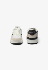 Sneaker bianche e beige realizzate in suede e pelle, con perforazioni sulla punta, dettagli neri e suola con motivo.