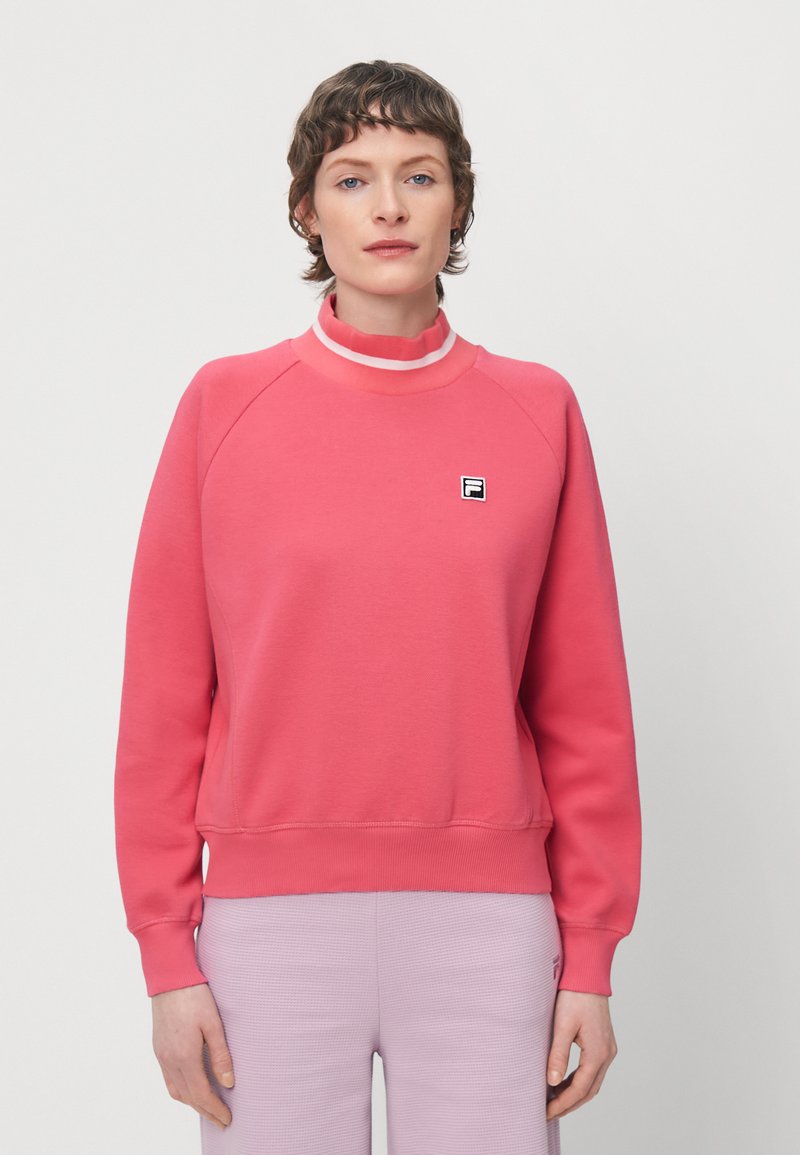 Felpa rosa con colletto alto, polsini a coste e un piccolo logo sul petto. Tessuto morbido con una superficie liscia.