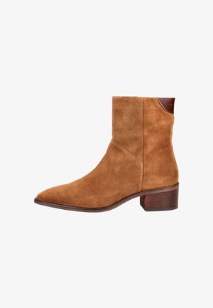 Braune Wildleder-Ankle-Boots mit spitzem Zeh und niedrigem Blockabsatz. Mit einem braunen Lederakzent am oberen Rand. Glatte Textur.