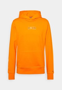 Pomarańczowa bawełniana bluza z kapturem ma przednią kieszeń, ściągacze na rękawach oraz biały napis "TOMMY HILFIGER" na klatce piersiowej. Gładka tekstura.