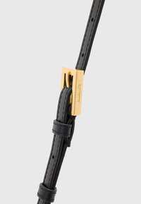 Schwarzer Lederarmband mit glatter Oberfläche, ausgestattet mit einer rechteckigen goldenen Schnalle und mehreren Anpassungslöchern. Sichtbare Nähdetails.