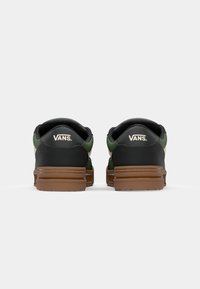 Sorte og grønne Vans sneakers med en tekstureret overdel, der har en brun gummisål og logodetalje på hælen.