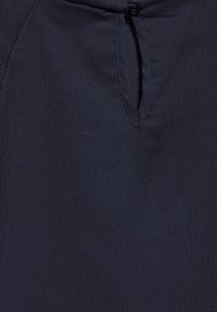 Tessuto blu navy con un sottile motivo a coste, caratterizzato da un'apertura a chiave nella parte superiore. Il materiale sembra morbido e liscio.
