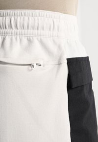 Kleurblokken rok in crème en zwart, met een elastische tailleband en een zijrits zak voor gemak. Zachte stof textuur.