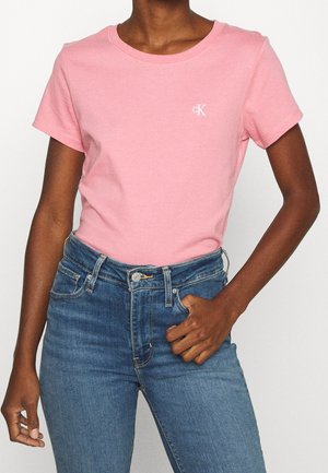 Roze katoenen t-shirt met korte mouwen, ronde halslijn en CK-logo in het wit. Gepaard met donkerblauwe denim jeans.