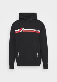 Felpa nera con strisce angolari bianche e rosse sul petto, testo "Tommy Jeans" in alto a destra, tasca a marsupio anteriore con coulisse bianca.