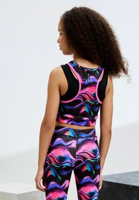Fekete sportos crop top színes absztrakt hullám mintákkal, versenypályás kialakítással és elasztikus pánttal. A szettet passzoló leggings egészíti ki.