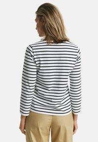 Gestreepte katoenen top met horizontale marineblauwe strepen op een witte achtergrond, met lange mouwen en een ronde hals.