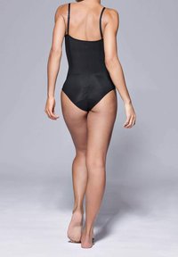 Costume da bagno intero nero con spalline regolabili, una silhouette aderente e una superficie liscia e opaca, che mette in risalto la schiena e le gambe.