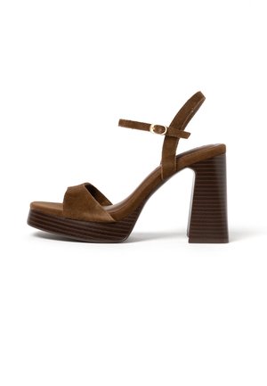 Hnedý semišový sandál na platforme s hrubým blokovým opätkom a pásikom okolo členka so zlatou malou prackou, zobrazený z bočného profilu.