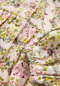 Material pentru rochie florală cu modele în nuanțe de roz, verde și mov. Prezintă mâneci volan, nasturi și un tiv zimțat pentru detalii suplimentare.