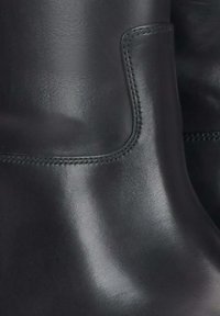 Černé kožené kotníkové boty s hladkým povrchem, zaoblenými hranami, jemným švem a bočním výřezem pro snadnější obouvání.