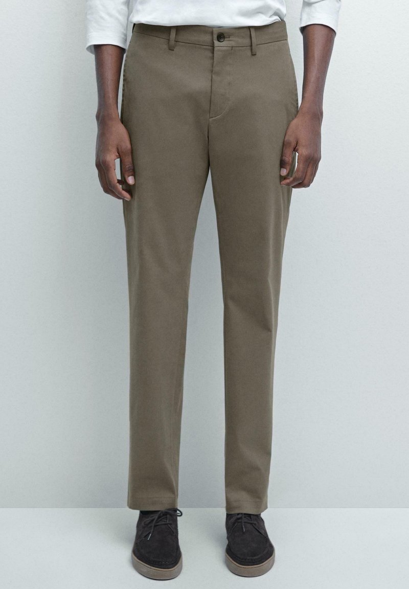Bruine chino's met een rechte pasvorm, voorzien van een knoopsluiting, riemlussen en zijzakken. G gedragen met donker suède schoenen.