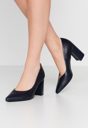 Granatowe skórzane szpilki z ostro zakończonym noskiem i szerokim obcasem. Gładka faktura, minimalistyczny design, brak widocznych wzorów.