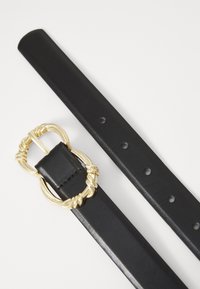 Ceinture en cuir noir avec une boucle décorative en or torsadé et plusieurs trous d'ajustement le long de la sangle.