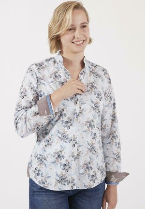 Chemise à boutons à motif floral en tissu léger, présentant une base bleu clair avec des accents beige, marron et bleu plus foncé.