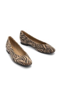 Une paire de chaussures plates à imprimé zèbre beige et noir avec des pointes et des talons bas sur un fond blanc.