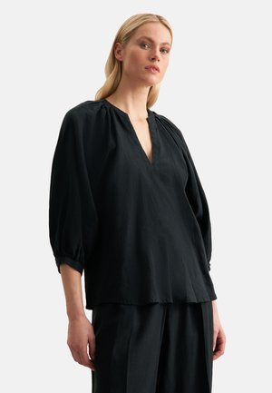 Schwarze, leichte Bluse mit V-Ausschnitt und gerafften Details an den Schultern. Mit lockeren, dreiviertellangen Ärmeln. Glatte Textur.