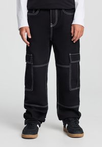 Pantaloni cargo neri con cuciture bianche, due tasche laterali e un fit rilassato. Realizzati in tessuto resistente per un uso pratico.