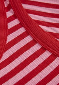 Tissu rayé avec des couleurs rouge et rose clair. Texture côtelée avec des bords bien marqués, présentant des rayures alternées larges et étroites.