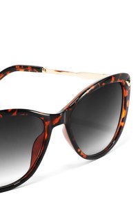 Sluneční brýle ve stylu kočičích očí s želvovinovým vzorem, černými a oranžovými odstíny, šedými gradientními čočkami a zlatými detaily na stranách.