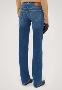 Pantalones vaqueros de mezclilla azul con un diseño de pierna recta, que presentan una etiqueta de cuero marrón en la cintura y dos bolsillos traseros.