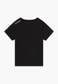 Camiseta de niño de manga corta en color negro con "KARL LAGERFELD" impreso en blanco en la parte superior del hombro izquierdo, cerca del escote.