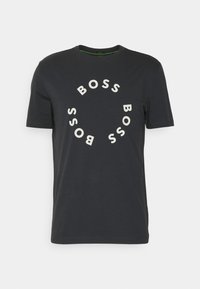Svart kortärmad t-shirt med rund halsringning, där "BOSS" är tryckt i vita bokstäver i ett cirkulärt mönster på framsidan.
