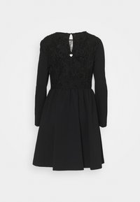 Musta mekko pitkillä hihoilla, jossa on teksturoitu, brodeerattu yläosa ja laskostettu hame. Avaus selkäpuolella, jossa on pieni sydänkoriste.