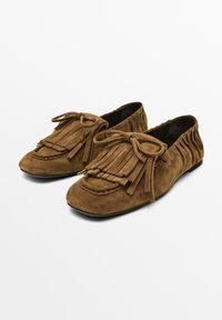 Brown suede moccasin-style shoes with fringed detailing, bow accents, and a rounded toe. Flexible construction with gathered back.