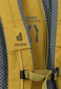Zaino Deuter con tessuto giallo e dettagli in rete grigia, spallacci regolabili e logo. Include fibbie laterali per il fissaggio.