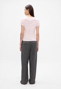 Φακελάκι κοντομάνικο μπλουζάκι σε ανοιχτό ροζ απόχρωση, σε συνδυασμό με γκρι ριγέ παντελόνι σε φαρδιά γραμμή, που διαθέτει δύο πίσω τσέπες με κούμπωμα.