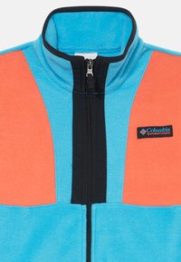 Fleecejacke in Hellblau und Koralle mit schwarzen Akzenten. Mit einem hohen Kragen und einem Frontreißverschluss ausgestattet. Columbia-Logo-Patch auf der Brust.