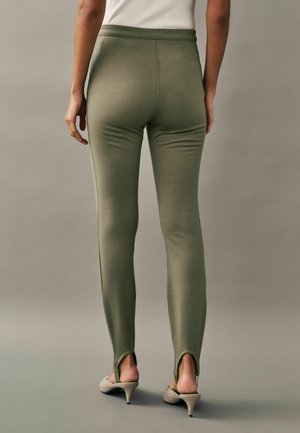 Colanți verde măsliniu, fabricați dintr-un material elastic, cu un design ajustat, slituri la gleznă și o talie netedă.