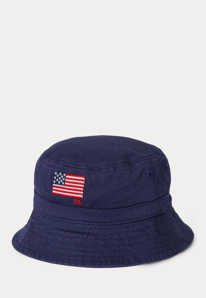 Sombrero tipo cubo de color azul marino hecho de algodón, con una pequeña bandera estadounidense bordada y el logo "RL" en un lado. Tejido texturizado, forma clásica.