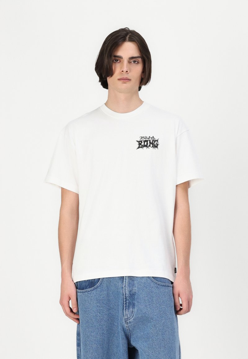 Hvid bomulds t-shirt med korte ærmer, rund halsudskæring, med sort grafisk tekst på venstre bryst. Sammen med lyseblå denimbukser.