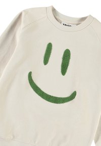Felpa color crema con un design di una faccina sorridente verde testurizzata. Il tessuto è morbido, con una vestibilità casual e colletto a costine.
