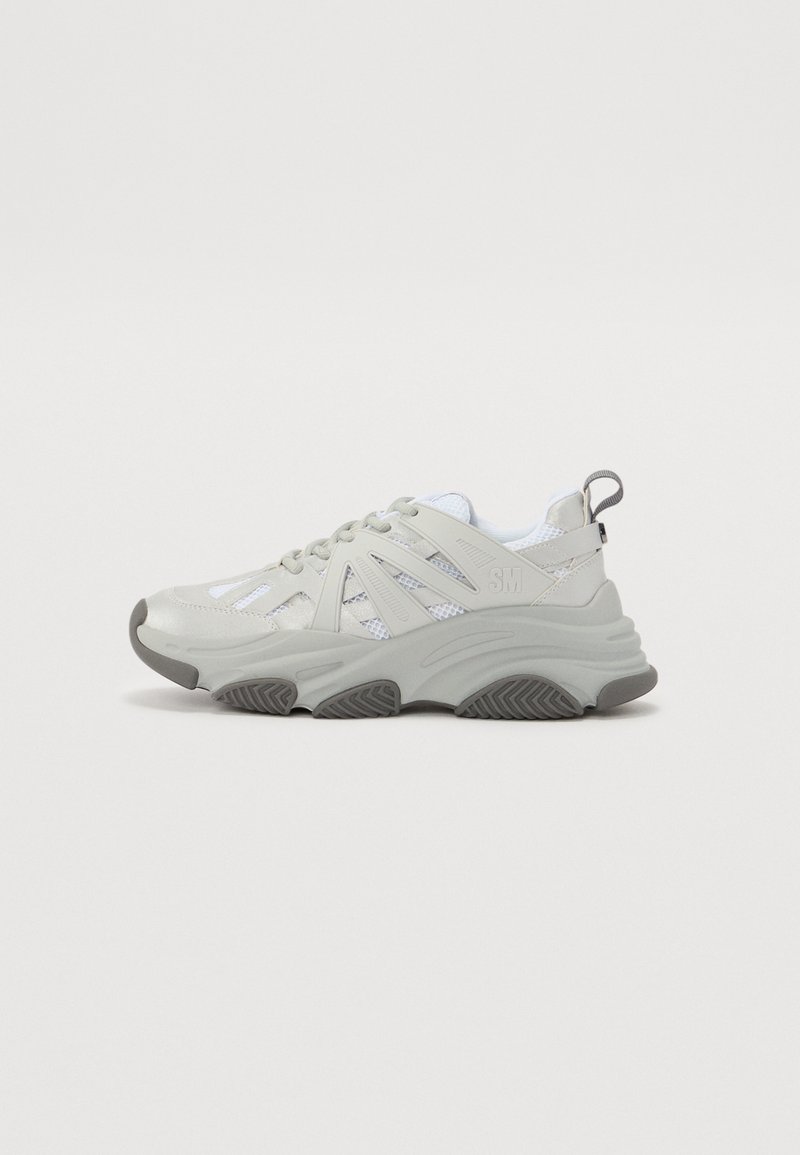 Sneakers grigi chiaro con pannelli in rete, suola in gomma testurizzata e accenti ben visibili. Presentano un linguetta sul tallone e un design con lacci.