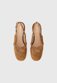 Chaussures slingback à imprimé léopard marron avec une semelle plate, des sangles croisées et une fermeture à boucle. Fabriquées en matériau doux imitation daim.