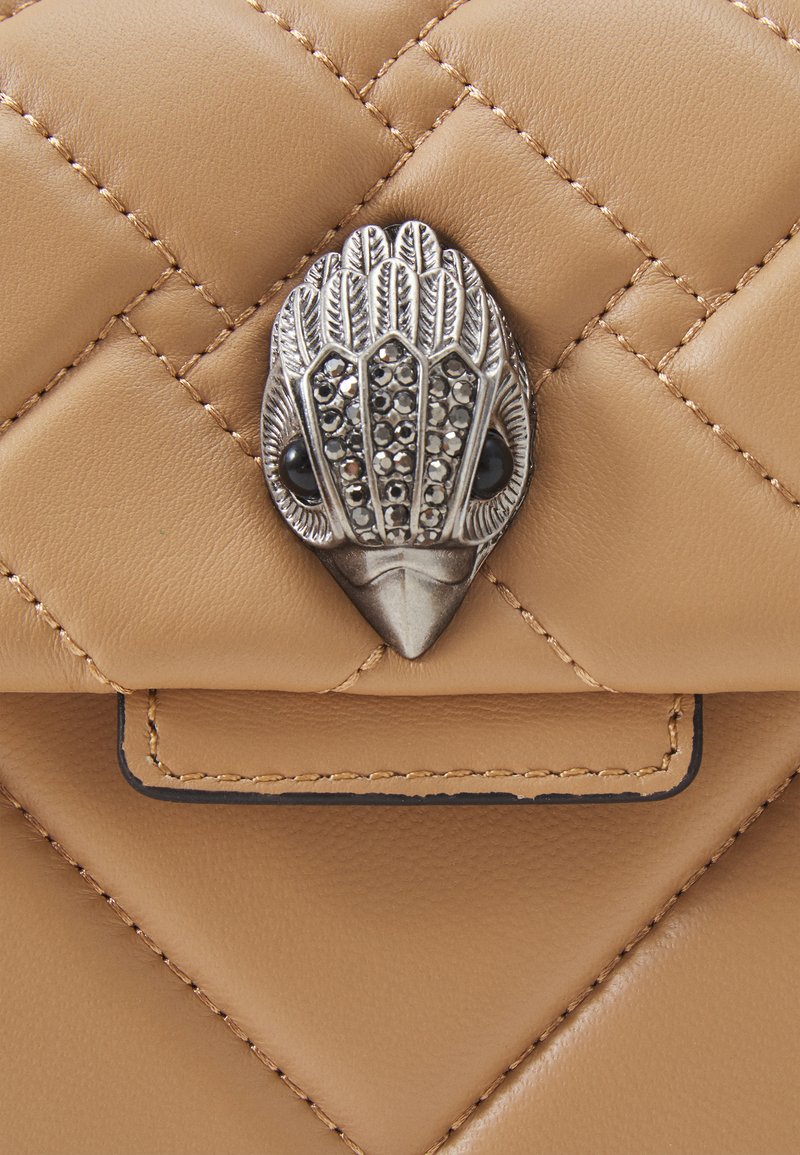 Wytłaczana torba ze skóry w kolorze brązowym z metalowym zapięciem w kształcie ptasiej głowy, ozdobiona czarnymi kamieniami szlachetnymi jako oczami oraz dekoracyjnymi wzorami.