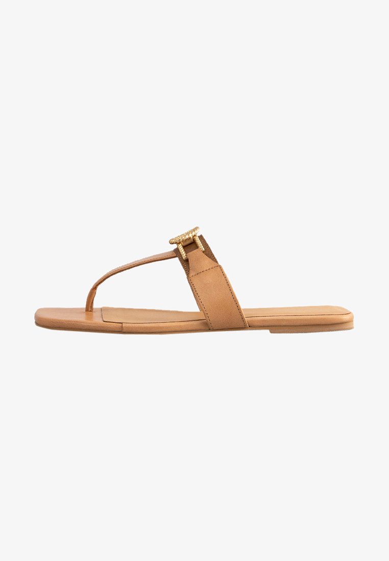 Tan leather sandal with a flat sole, minimalist design, thong style strap, and gold-tone accent detail on the strap.