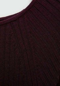 Tissu tricoté bordeaux foncé avec une texture côtelée diagonale et verticale et un col arrondi visible en haut.