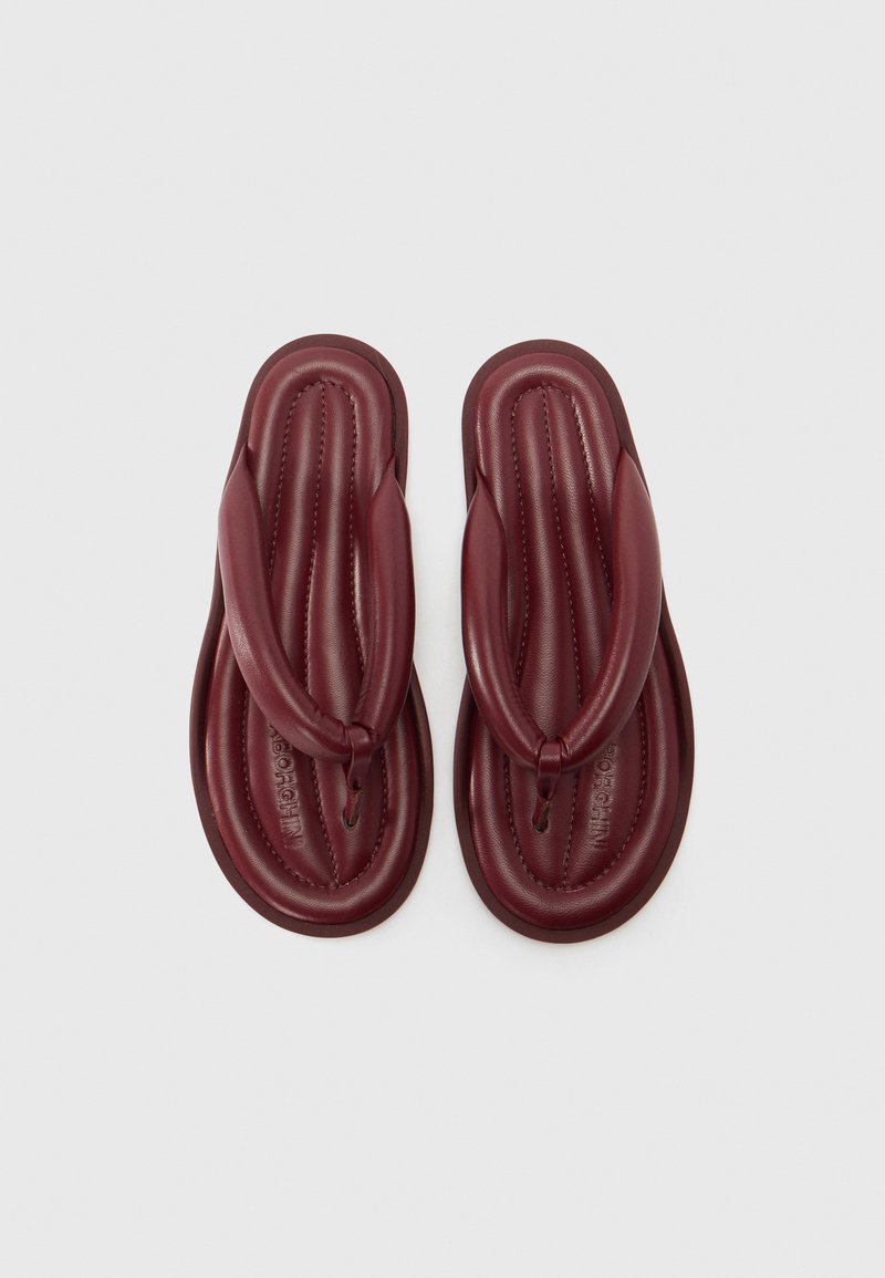 Burgundy flip-flops with a padded, textured thong strap and a contoured outsole. Smooth material with stitched accents.
