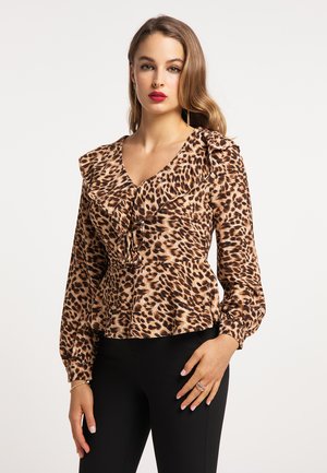 Bluse mit Leopardenmuster aus weichem Stoff, mit Rüschenausschnitt, langen Ärmeln und taillierter Passform. Kombiniert mit schwarzen, enganliegenden Hosen.