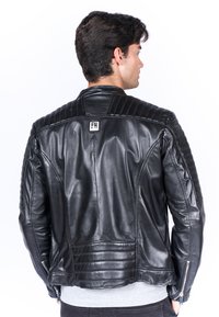 Giacca in pelle nera con un design trapuntato sulle spalle, retro testurizzato e dettagli in zip argentati sulle maniche.
