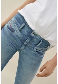 Ljust blå denimjeans med hög midja, dekorativa sömmar på fickan och en klassisk femficksdesign.