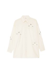 Chemise crème à manches longues avec col et boutons, ornée de broderies florales blanches aux centres noirs sur le devant, les manches et les côtés inférieurs.